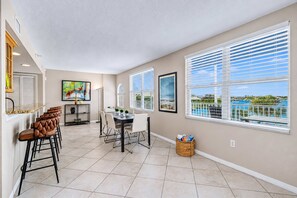 A spacious room with a dining area, a kitchen, and large windows with blinds. - Third floor condo with pool access fast WiFi central AC and WD snowbirds OK (Clearwater)