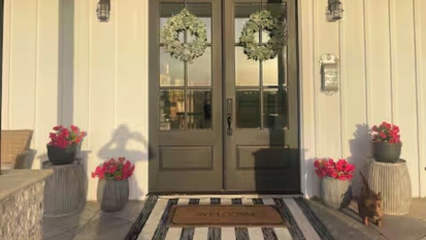 A front door with two wreaths, a welcome mat, and potted plants on either side. - Modern farmhouse with a pool (Cat Spring)