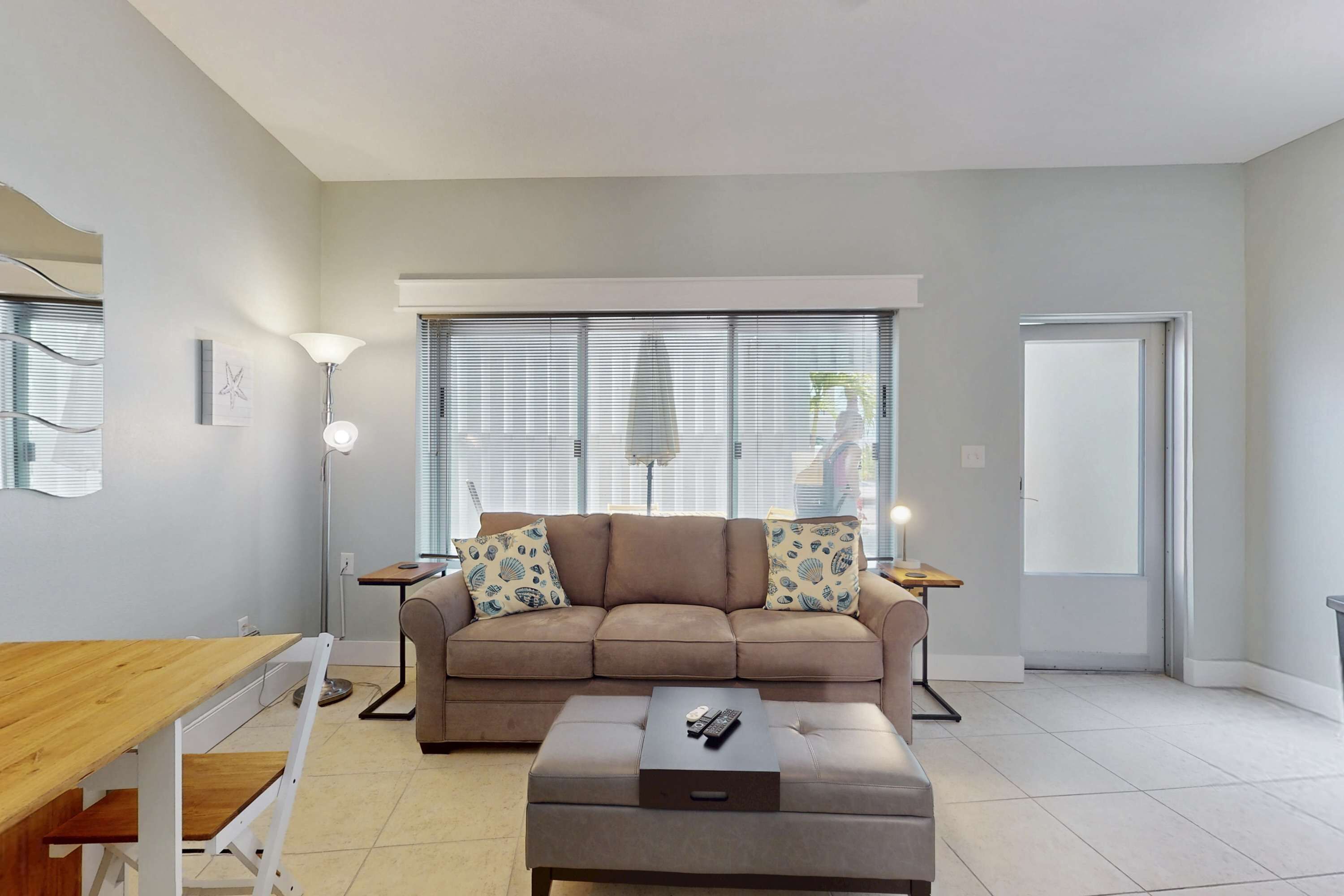 Una sala de estar moderna con un sofá color beige, una mesa de centro de madera y una lámpara de pie.