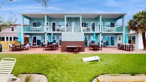A two-story bungalow with a patio area, outdoor seating, and a sign reading "BUNGALOW Beach Place". - Gulf front condo top floor beach access full kitchen and central AC (Indian Shores)