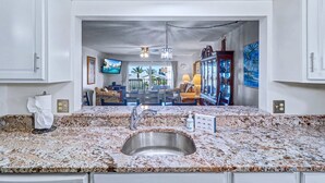 A kitchen with a granite countertop, stainless steel sink, and a ceiling fan. - Waterfront condo with pool hot tub tennis and beach access (Indian Rocks Beach)