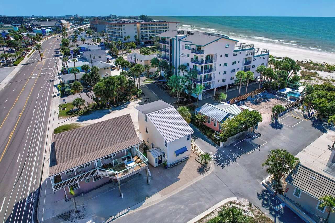 Un hôtel situé sur la côte, composé de plusieurs bâtiments, offrant une vue sur la plage et disposant d’un parking.