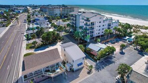 Un hotel frente al mar con varias construcciones, vistas a la playa y una zona de estacionamiento.