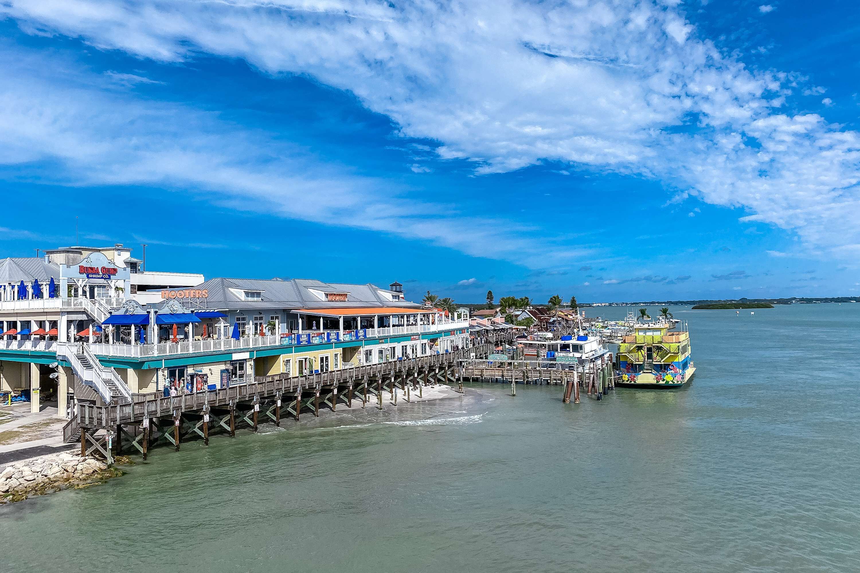A pier with a restaurant named "Booters" and a colorful boat docked at the end.