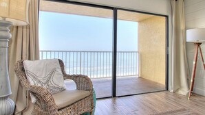 Una sedia in vimini con un cuscino a forma di stella, un pavimento in legno e vista sul mare attraverso una porta in vetro.