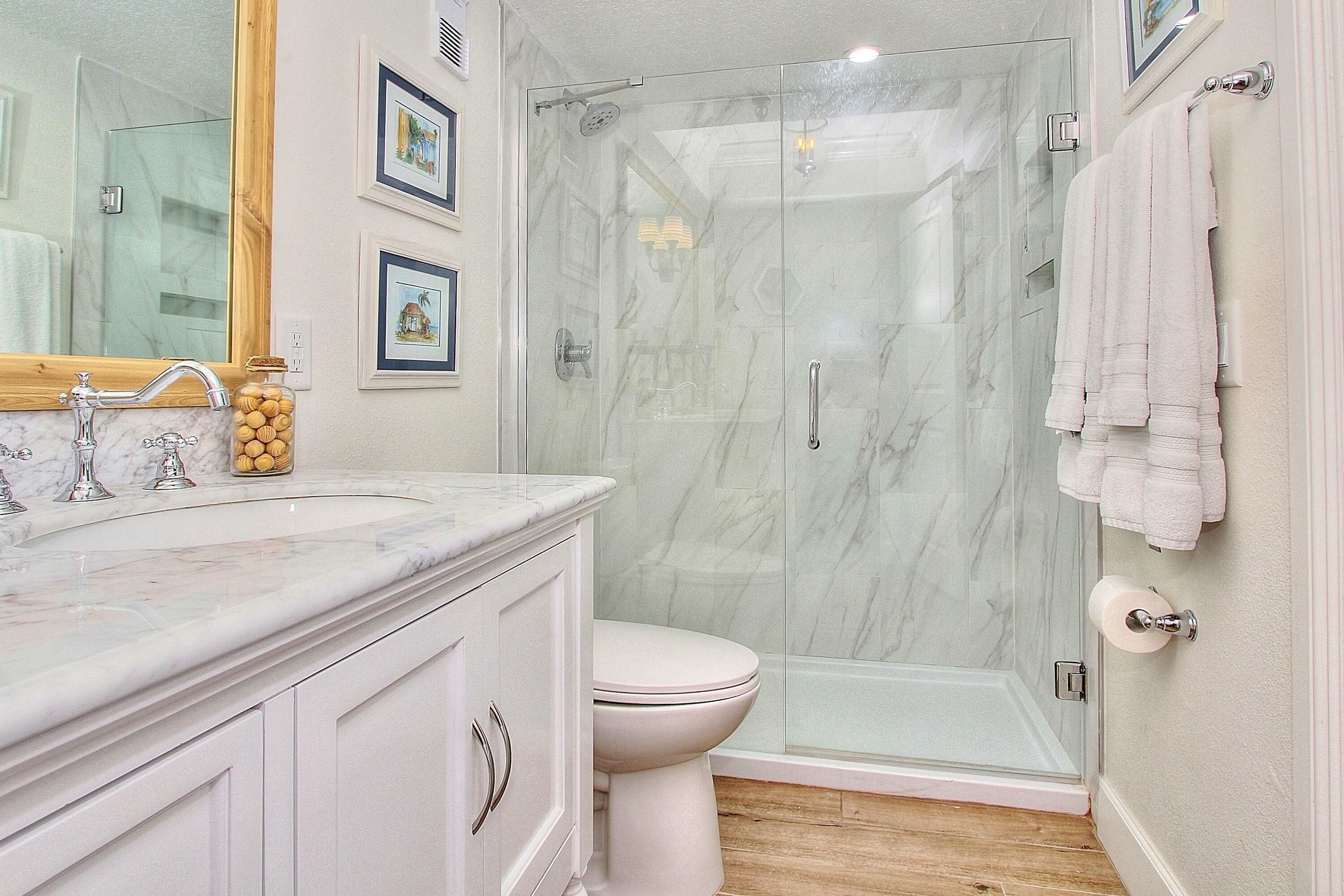 Une salle de bain avec un lavabo en marbre, des toilettes et une douche à parois de verre.