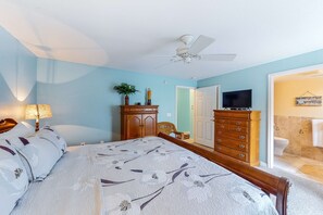 A bedroom with a bed, dresser, and ceiling fan.