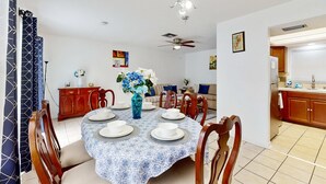 A dining area with a round table set for six, wooden chairs, a vase with flowers, and a ceiling fan. - Centrally located dog friendly comfortable home with AC and WD (Largo)