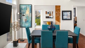 Un'area pranzo moderna con una ventola a soffitto in legno, un tavolo da pranzo con quattro sedie e un'ampia finestra che offre vista sulla città.