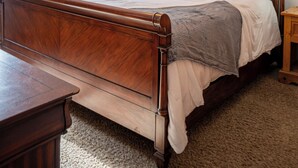 Ein Schlafzimmer mit einem hölzernen Bett, einem Nachttisch, einer Lampe und einer Deckenleuchte.