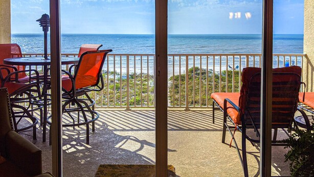 Ein Balkon mit Blick auf das Meer, ausgestattet mit Sitzgelegenheiten und einem Tisch.