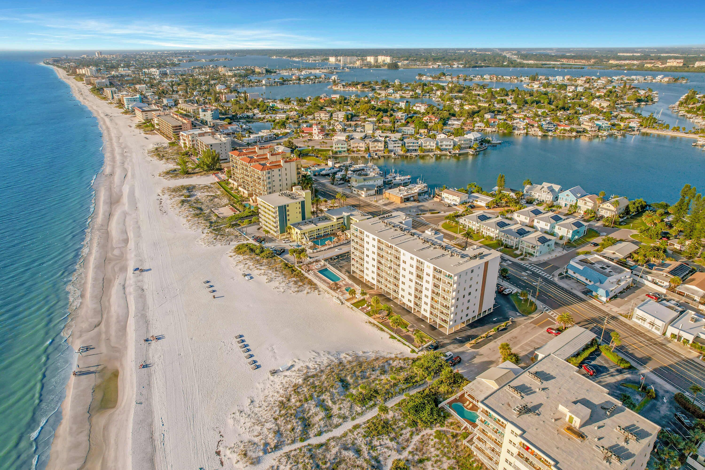 Un hôtel situé sur la côte, avec vue sur la plage, plusieurs piscines et un port de plaisance.