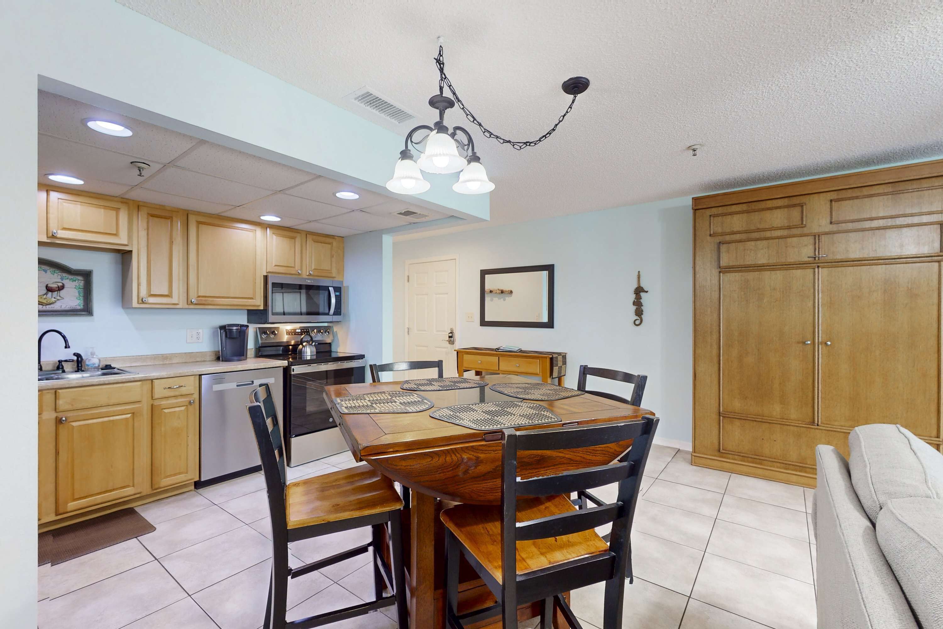 A compact kitchen with wooden cabinets, a dining table with chairs, and a built-in oven.