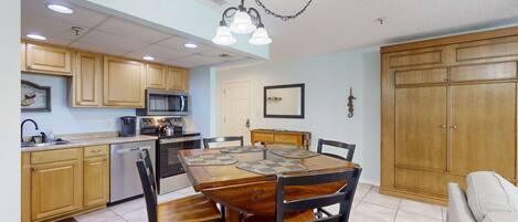 A compact kitchen with wooden cabinets, a dining table with chairs, and a built-in oven.