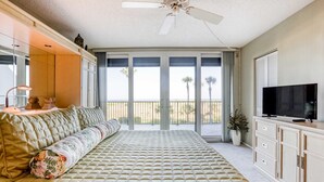 A spacious room with a large bed, a television, and a balcony with a view of palm trees. - Second floor condo with pool and tennis court private WD and central AC (Clearwater)