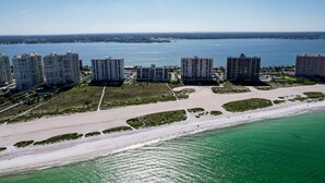 An aerial view of a coastal area with high-rise buildings, a beach, and a body of water. - Second floor condo with pool and tennis court private WD and central AC (Clearwater)