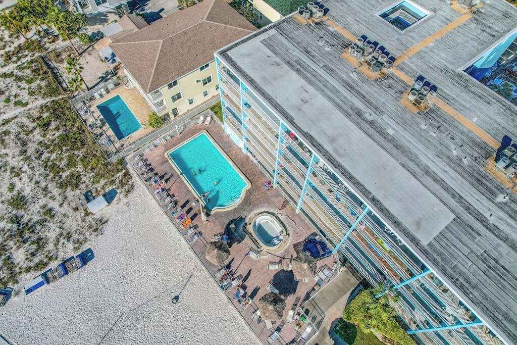 Un hotel con piscina en la azotea, zona de piscinas separada y playa.