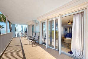 Ein Balkon mit Meerblick, eine Essecke mit Stühlen und ein Wohnzimmer mit Sofa und rundem Tisch.