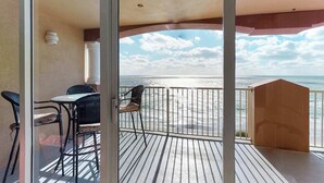 A balcony with a view of the beach and ocean.