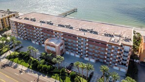 A multi-story hotel with a rooftop terrace, a parking area, and a view of the ocean.