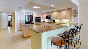 A spacious kitchen with a large island, bar stools, and modern appliances.