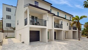 A modern multi-story residential building with a flat roof, multiple balconies, and a paved driveway. - Modern dog friendly townhome close to the Gulf and beaches shopping and dining (Treasure Island)
