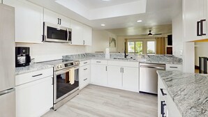 A modern kitchen with white cabinets, a stainless steel microwave, an oven, and a dishwasher. - Modern dog friendly townhome close to the Gulf and beaches shopping and dining (Treasure Island)
