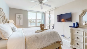 Ein Schlafzimmer mit einem Bett, einem Deckenventilator, einem Fernseher und einer Kommode.