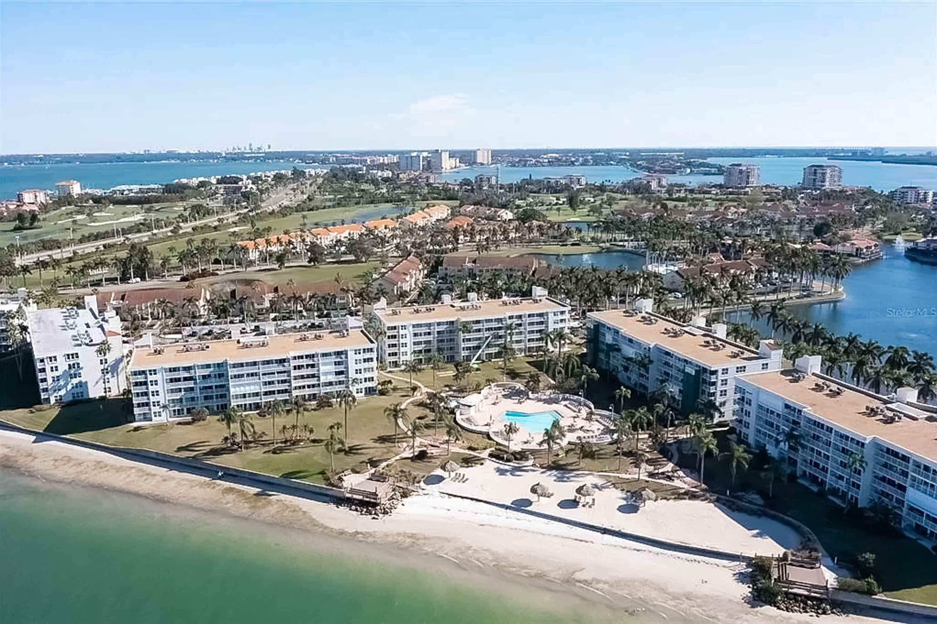 Un resort con varias construcciones, piscina y playa.