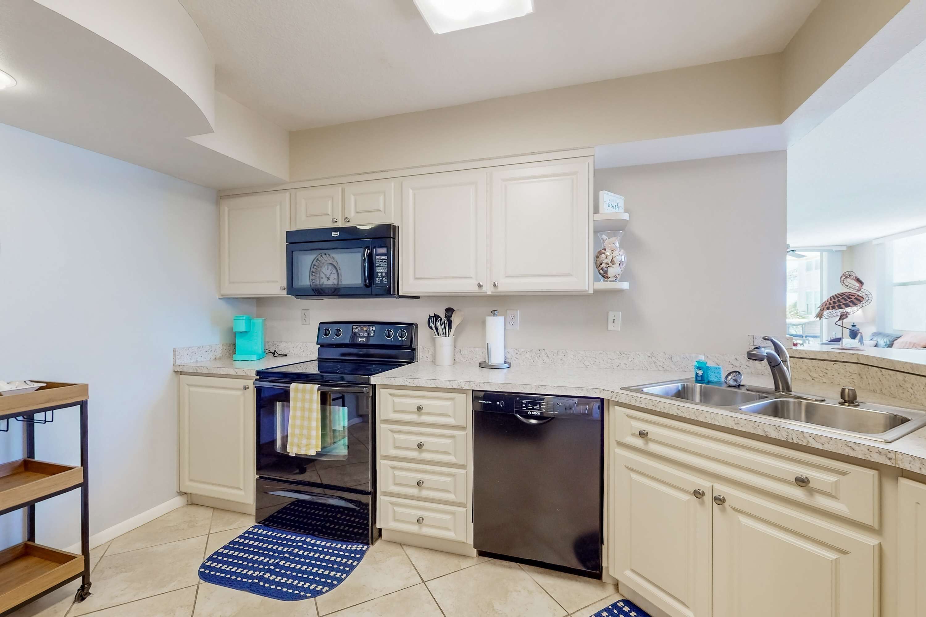 A modern kitchen with white cabinetry, a black microwave, a dishwasher, and a stainless steel sink.
