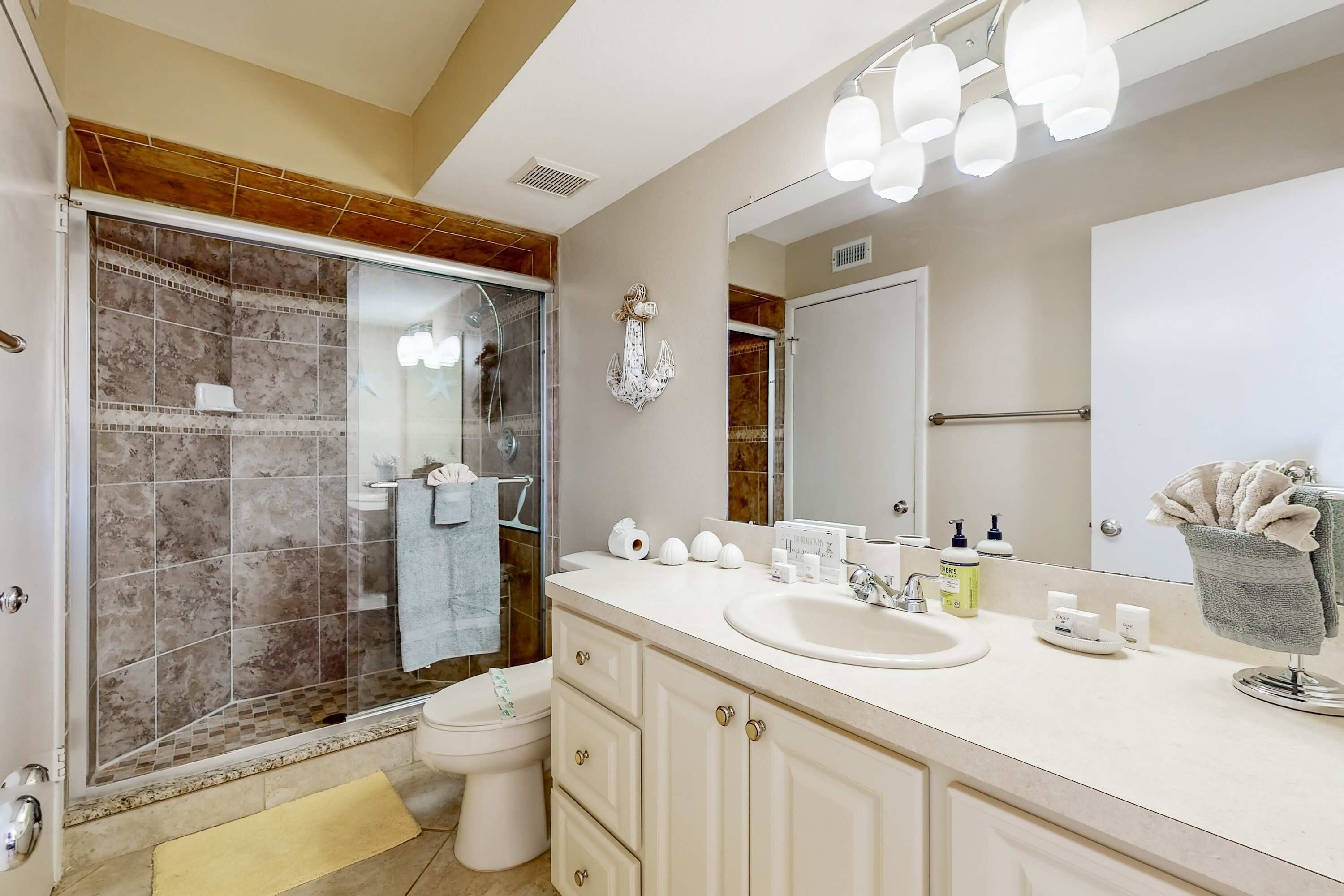 A bathroom with a shower, toilet, sink, and vanity.