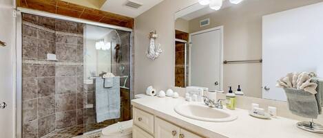 A bathroom with a shower, toilet, sink, and vanity.