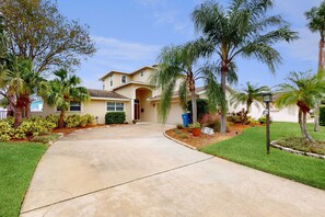 A residential house with a driveway, palm trees, and a well-maintained lawn.