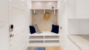 A compact, well-lit room with a built-in bench, a hat on the wall, and a small shelf with hooks. - Gulf front penthouse on Belleair Beach (Belleair Beach)