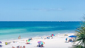 A beach with white sand, clear blue water, and a distant pier. - Gulf front penthouse on Belleair Beach (Belleair Beach)