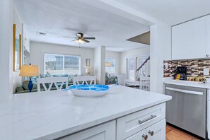 A modern kitchen with white cabinetry, a marble countertop, and a built-in dishwasher. - Delightful condo with beach and pool access washer dryer (Belleair Beach)