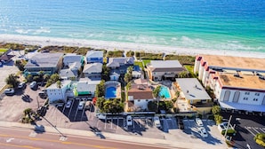 An aerial view of a coastal residential area with houses, a beach, and a parking lot. - Delightful condo with beach and pool access washer dryer (Belleair Beach)