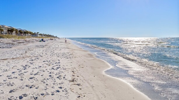 A beach with footprints, a clear sky, and a distant lighthouse. - Delightful condo with beach and pool access washer dryer (Belleair Beach)