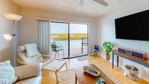 Ein geräumiges Wohnzimmer mit Balkon, einem Flachbildfernseher und einem Holztisch.