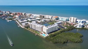 Ein Luftbild eines Hotelkomplexes an der Küste mit mehreren Gebäuden, einer Marina und einer großen Grünanlage.