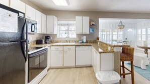 Une cuisine moderne avec des meubles blancs, un réfrigérateur noir et un plan de travail en granit.