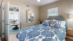 Une chambre à coucher avec un lit, un ventilateur de plafond, une commode, un miroir et une fenêtre.