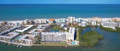 Vista aérea de una zona hotelera costera con varios edificios, un puerto deportivo y una gran extensión de agua.