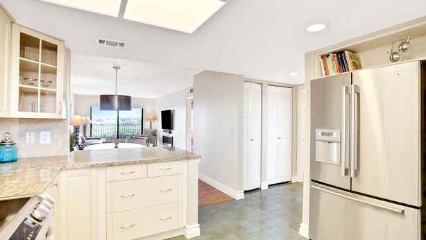 A modern kitchen with a central island, built-in cabinets, a stainless steel refrigerator, and a skylight. - Elegant condo with water view near beach pool and hot tub fast WiFi and AC (Indian Shores)