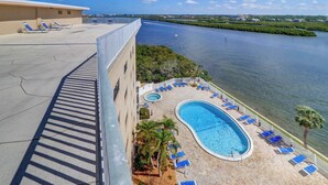 A rooftop pool area with lounge chairs, a swimming pool, and a view of a river. - Elegant condo with water view near beach pool and hot tub fast WiFi and AC (Indian Shores)