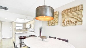 A modern dining area with a round marble table, black chairs, a hanging light fixture, and decorative wall art. - Elegant condo with water view near beach pool and hot tub fast WiFi and AC (Indian Shores)