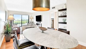 A modern dining area with a round marble table, black chairs, and a hanging light fixture. - Elegant condo with water view near beach pool and hot tub fast WiFi and AC (Indian Shores)