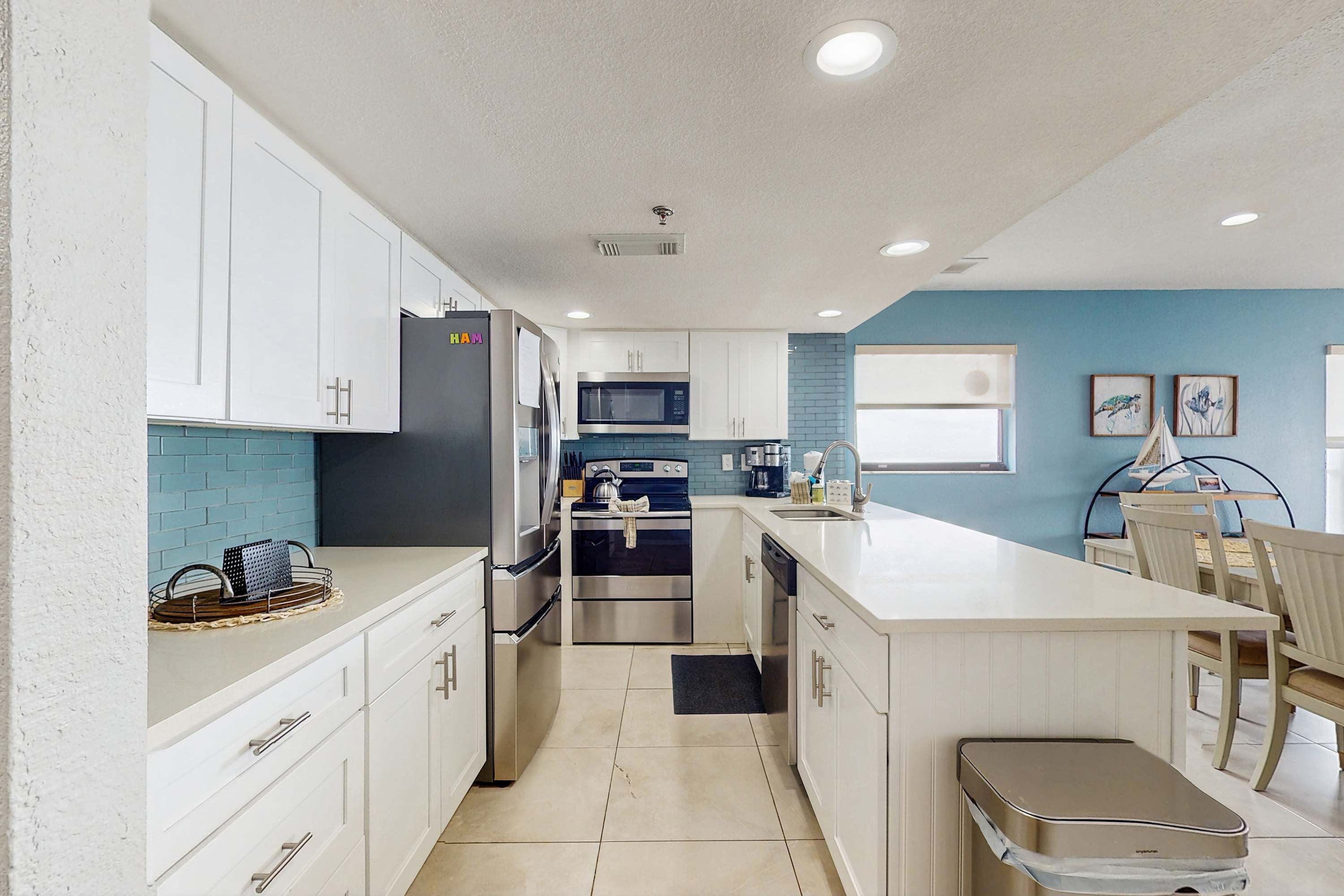 Une cuisine moderne avec des meubles blancs, un îlot central, un four à micro-ondes et une cuisinière.