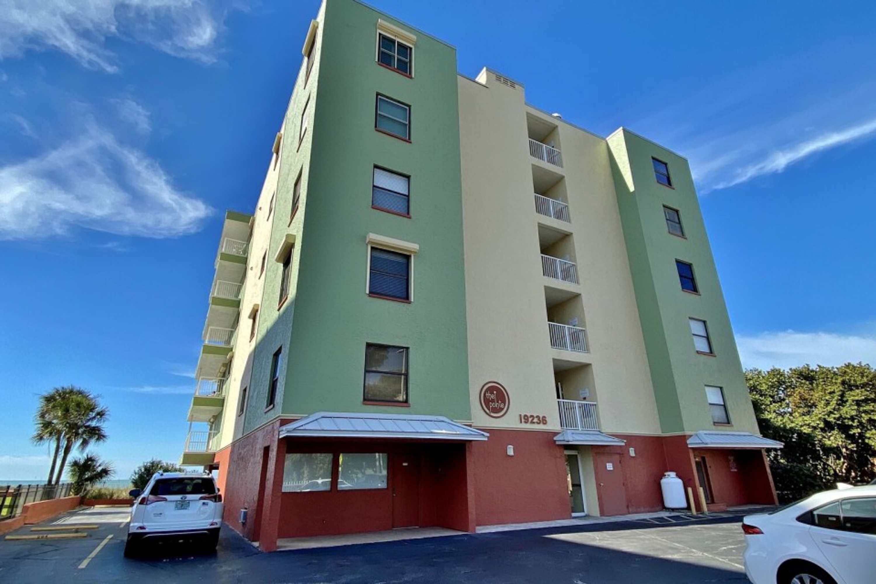 Un immeuble à plusieurs étages, doté d’une façade verte et beige, portant le numéro 19236, et comprenant des balcons ainsi qu’une entrée au niveau du rez-de-chaussée.