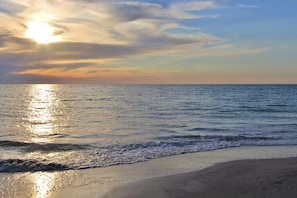 A beach with the sun reflecting off the water, creating a calm and serene atmosphere.